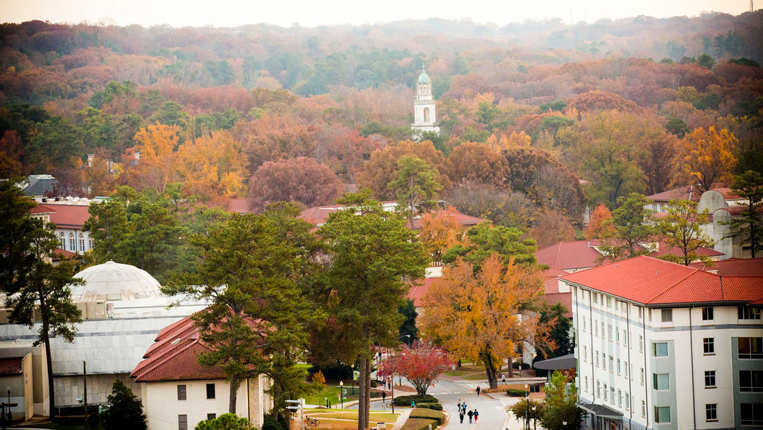 view of campus in the fall from above with red tile roofs and colorful trees